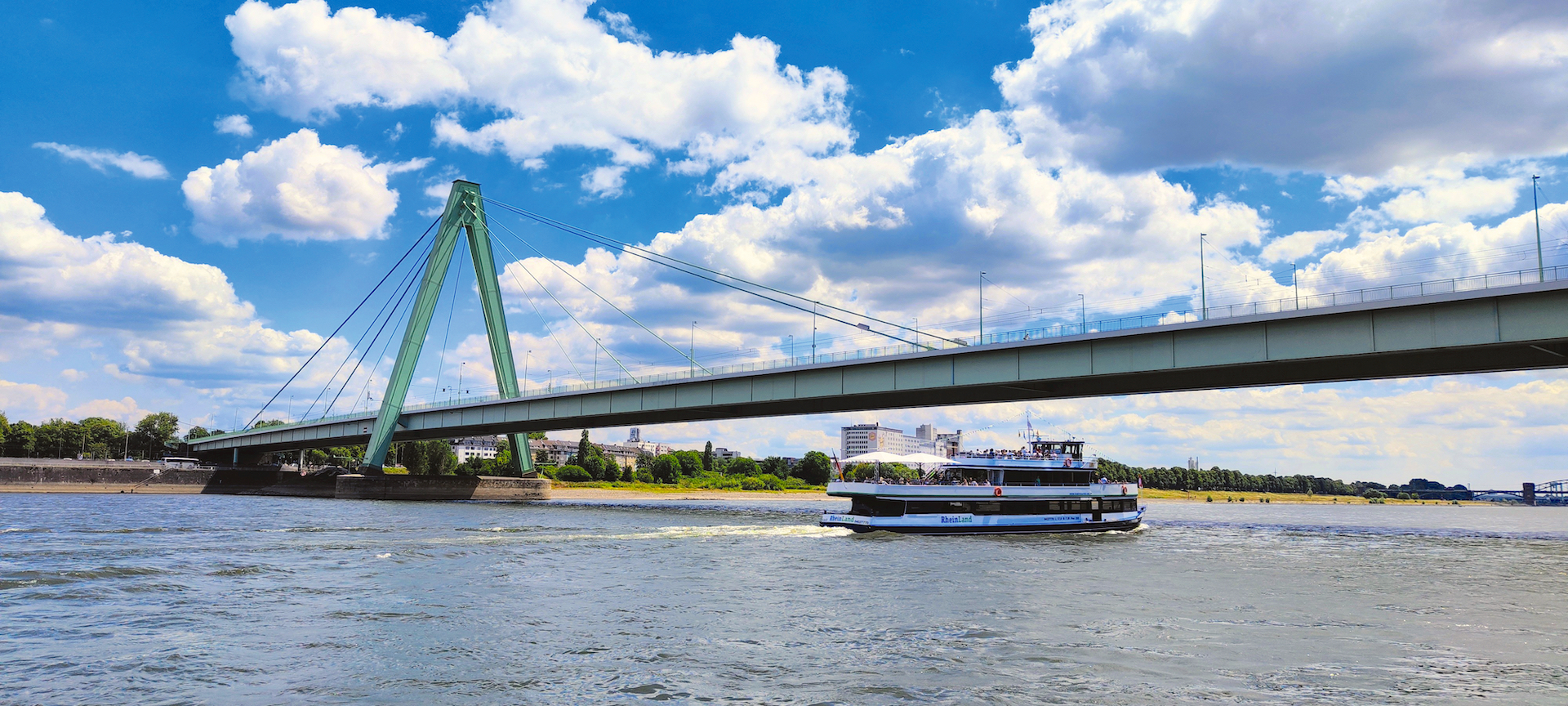 Flussschiff vor Kölner Brücke und Rhein