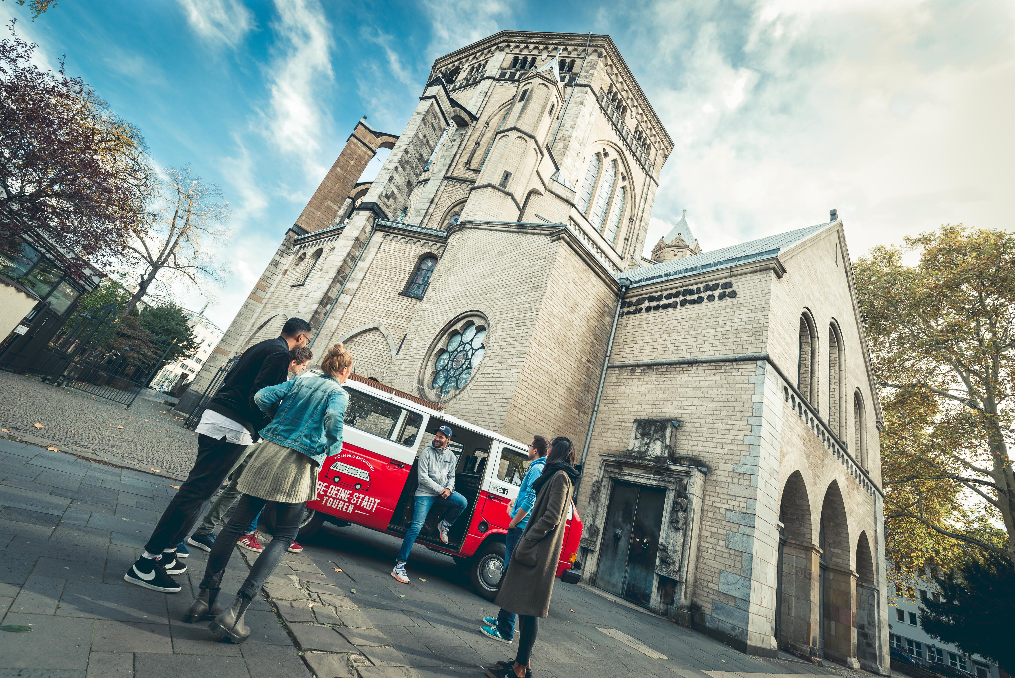 VW Bully mit Reisegruppe vor Kölner Kirche